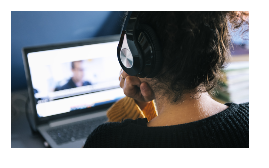 Woman with headphones watching video on a laptop